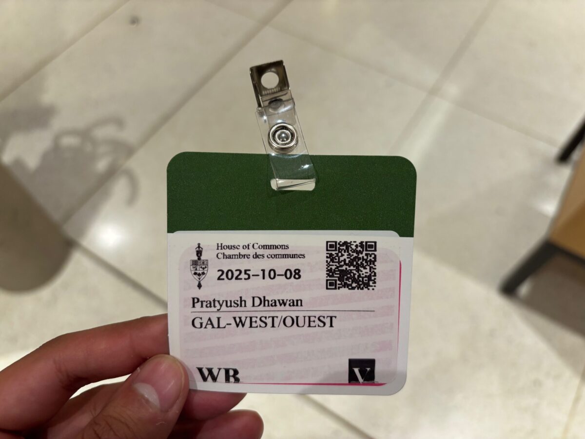 A hand holds a pass to the House of Commons in Canada